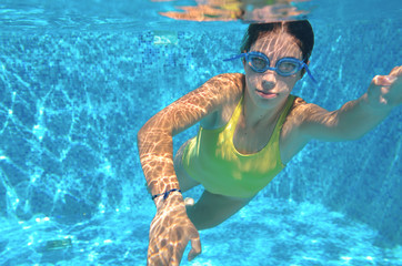 Young girl swimmer swimming freestyle in pool, under water view, sport and fitness concept
