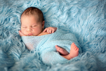 Happy smiling newborn baby in wrap, sleeping happily in cozy fur © Tomsickova