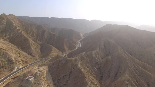 Aerial view of desert valley in Muscat bay region, road in desert surrounded by mountains, Oman, sultanate on Arabian Peninsula from above, 4k UHD 