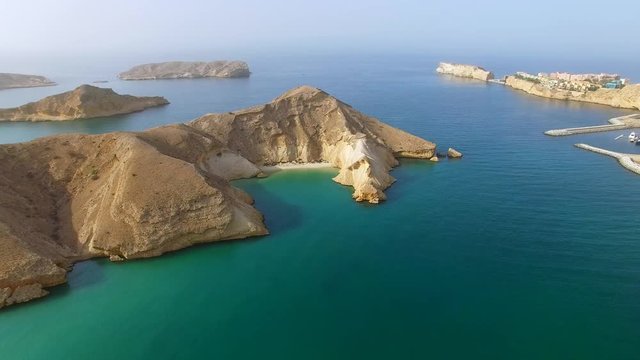 Aerial view of Muscat bay, dive resort, day trip and relaxing area, turquoise crystal clear water of Indian Ocean, beaches, blue lagoons and small islands from above, Oman, Arabian Peninsula, 4k UHD 