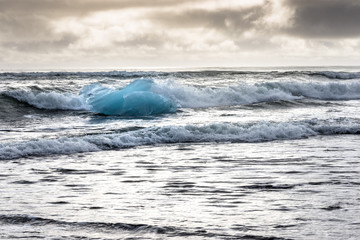 Angeschwemmter Eisberg in den Wellen am Black Diamond Beach in Südisland