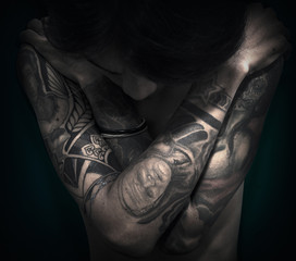 A man half body close up photo with tattoo on the both arms
