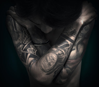 A man half body close up photo with tattoo on the both arms
