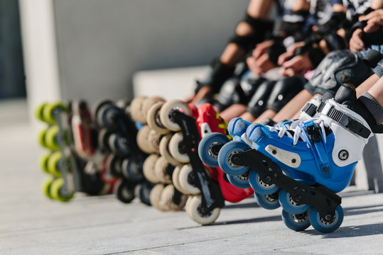 Feet of rollerbladers wearing inline roller skates sitting in outdoor skate park, Close up view of wheels befor skating