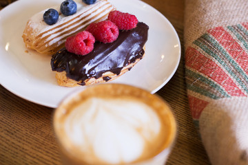 Cappuccino and cake with berries on table. Closeup.