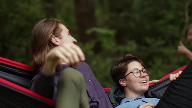 Friends Hang Out In Hammock, Their Other Friend Gives Them A Thumbs Up, Man Laughs