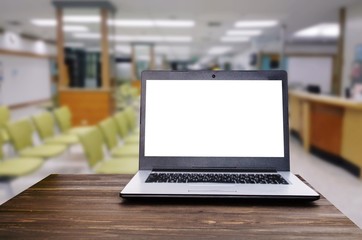 Laptop notebook computer with white blank screen on wooden desk with blurred view of empty chairs in clinic or hospital, heart health care and medical technology concept, selective focus, copy space