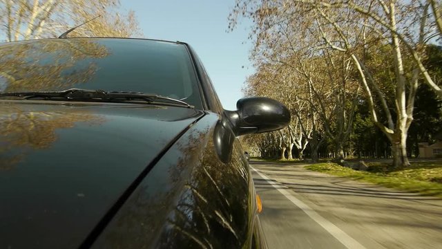 Driving a car, windshield reflection. Hood side reference. Mounted camera, front view. Black car ride. Country road, trees on the side, blue sky, day. Real Time Speed. HD. Right side wheel driving UK