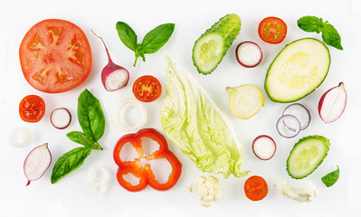 Colorful set of vegetables of red and green color isolated on white background top view, design for vegetable menu. Tomato onion cucumber sweet pepper zucchini Peking cabbage cauliflower radish basil.