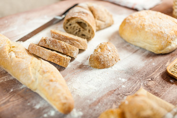 Fresh bread slice and cutting knife on rustic wooden table