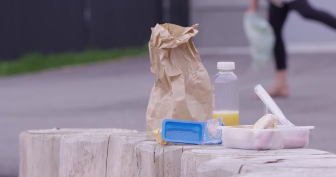 prepack school lunch outside  teacher picking up garbage in background
