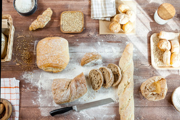 Fresh bread slice and cutting knife on rustic wooden table. Top View