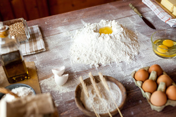 Egg yolk in flour on a wooden table in a bakery. Rural or rustic style.