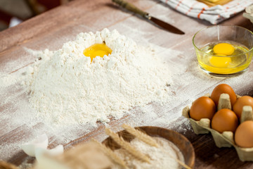 Egg yolk in flour on a wooden table in a bakery. Rural or rustic style.