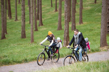 Young family in warm clothes cycling in autumn park
