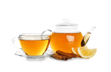 Glass teapot and cup with aromatic hot cinnamon tea on white background