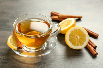 Cup with aromatic hot cinnamon tea and lemon on table