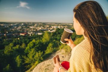 young pretty woman sitting on the peak of the hill