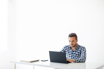 Portrait of handsome man typing on laptop on white background