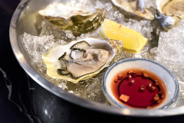 Fresh oysters with sauce and lemon on ice