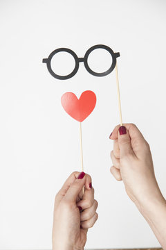 female hand holding glasses and heart photo booth prop