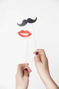 female hand holding mustache and lips photo booth prop