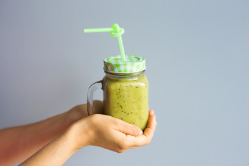 Healthy green smoothie in woman's hand. Vegan, raw food, detox and diet lifestyle.