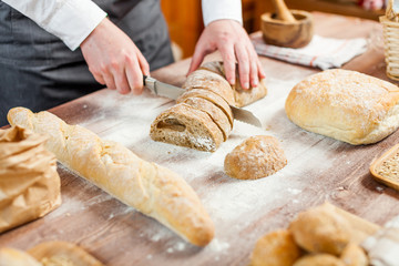 Male hands cutting fresh bread on the wooden table, selective focus