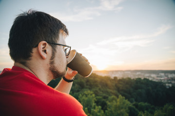 man sitting on the top of the hill with cup of coffee