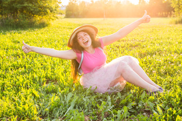 Beautiful young laughing naughty woman sitting on the grass and smiling