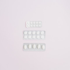 Flat lay medicine pills on pink background. Top view medical texture.