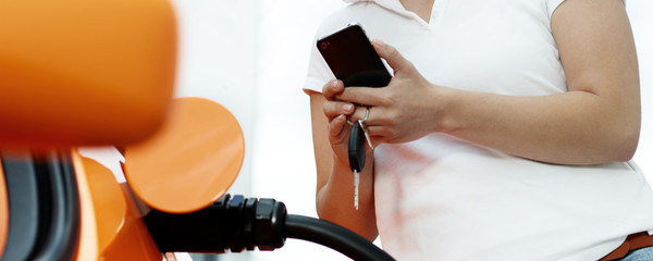 Woman with cellphone loading electrically powered car 