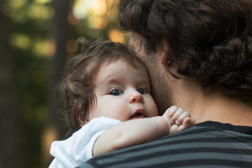 Close up of young father holding his newborn baby. Focus on the baby's blue eyes