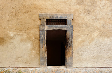 a dark and old rectangle entrance without door in a stone wall