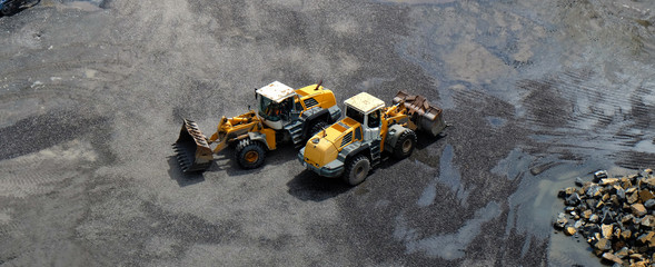 Two wheel loader vehicles with front buckets passing each other, crossing in opposite directions...