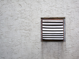 Commercial Exhaust Vent on Gray Stucco Wall; water stain streaked
