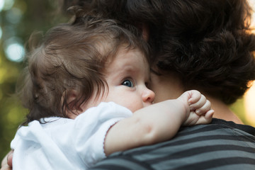 Little Girl resting on her father's shoulder. Happy sweet girl hugging her father on the forest background