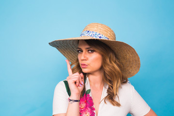 portrait of attractive young woman with finger on lips gesturing silence, studio shot