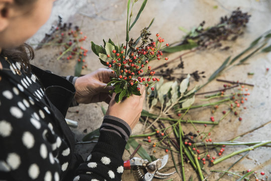 Woman&rsquo;s hands working on an autumn flower arrangement