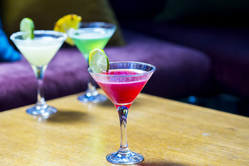 Three colorful cocktails in martini glasses