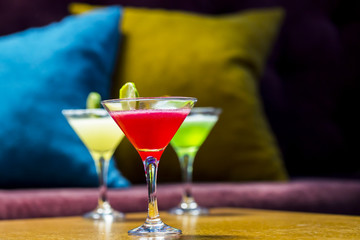 Three colorful cocktails in martini glasses