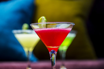 Three colorful cocktails in martini glasses