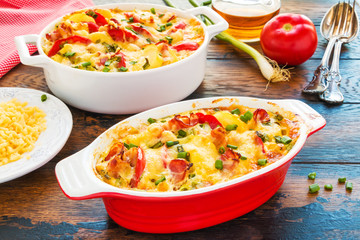 Homemade cheesy Belgian casserole with smoked bacon, potatoes and tomatoes on the wooden rustic...