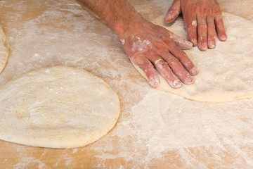 Men hands sprinkle a dough with flour. Man preparing pizza dough.