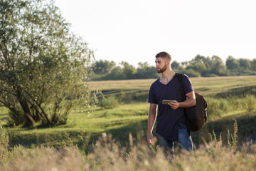 Naklejka na ściany i meble Young man on hike in nature using phone