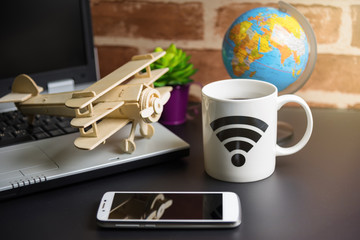 Table of office stuff Business man with Laptop, Wireless mouse, Smart phone, Toy wooden plane and Coffee Cup WIFI symbol.Concept office Business man workplace.