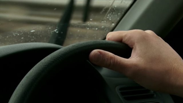 Driving on highway, rain. Detail of two Hands on the steering wheel, windshield POV. Right side wheel / driving - UK