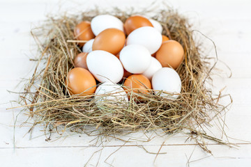Fresh country eggs with straw on rustic wooden white table