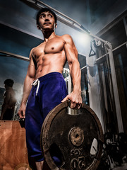 Fototapeta na wymiar Asian bodybuilder athlete man standing in a training gym and doing fitness with barbell, show perfect and strong six packs abs, torso, chest, biceps, triceps