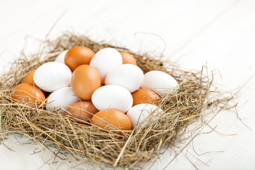 Fresh country eggs with straw on rustic wooden white table